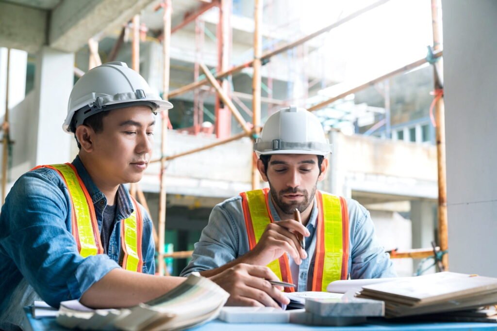 young asian engineers caucasian engineer colleagues site inspector discuss together using notebook computer paper blueprint building construction sitehome renovation ideas concept