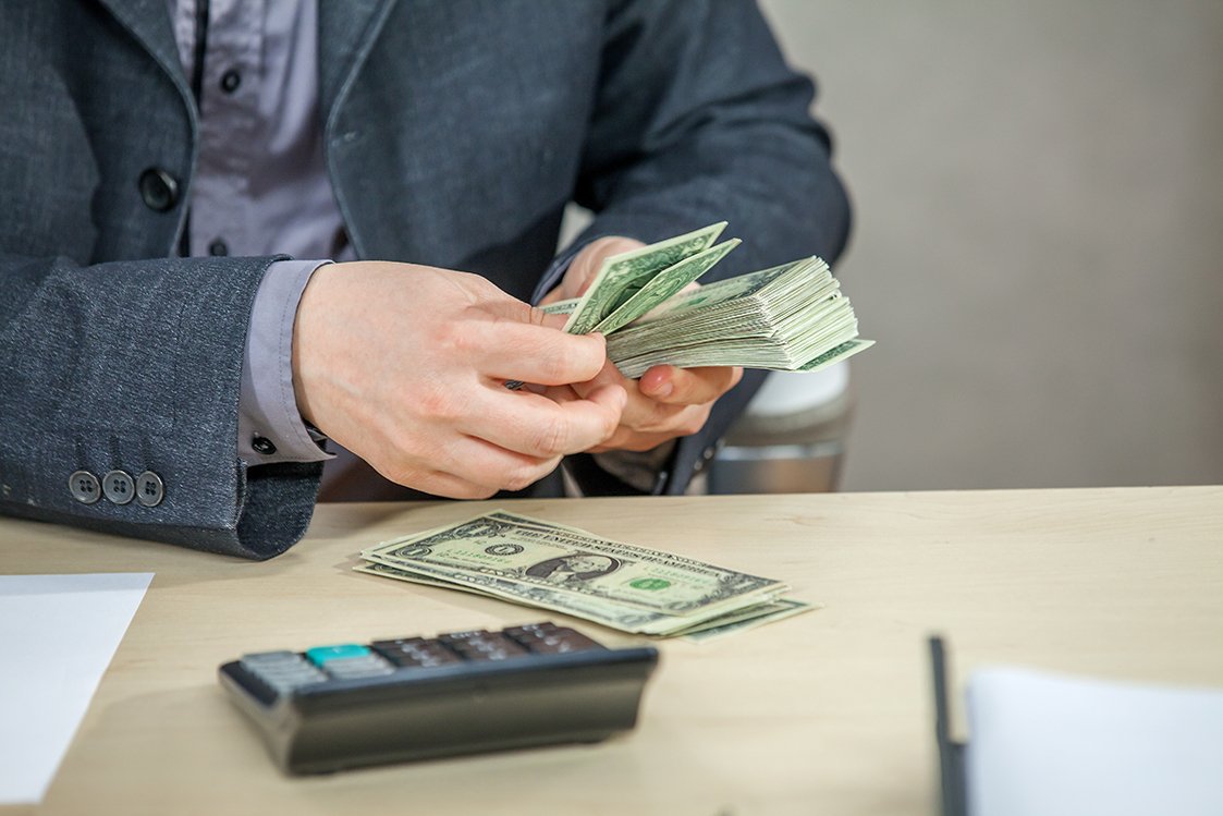 Young businessman working from his office and counting cash money